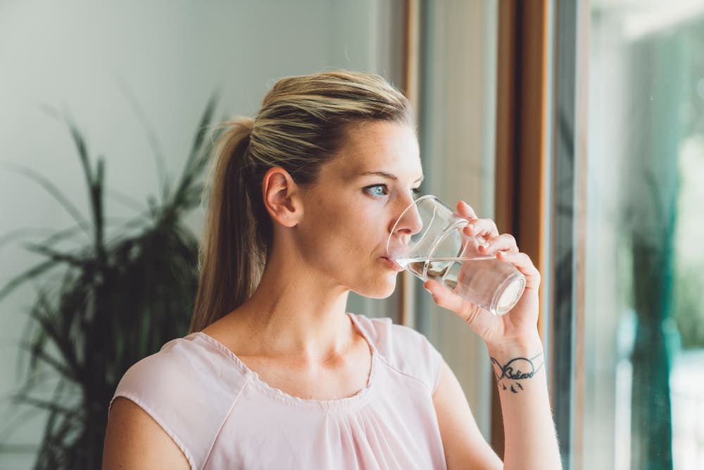 mujer bebiendo vaso de agua por sensacion de boca seca persistente garantia dental mujer bebiendo vaso de agua por sensacion de boca seca persistente garantia dental